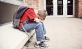 Depressed,Student,Sitting,Outside,Of,School,Hiding,His,Face