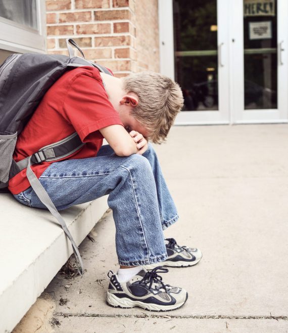 Depressed,Student,Sitting,Outside,Of,School,Hiding,His,Face