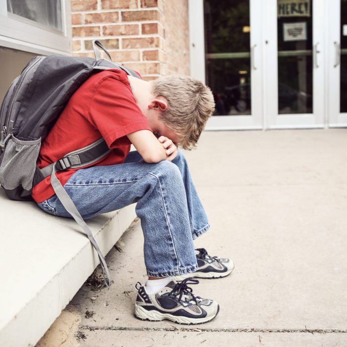 Depressed,Student,Sitting,Outside,Of,School,Hiding,His,Face